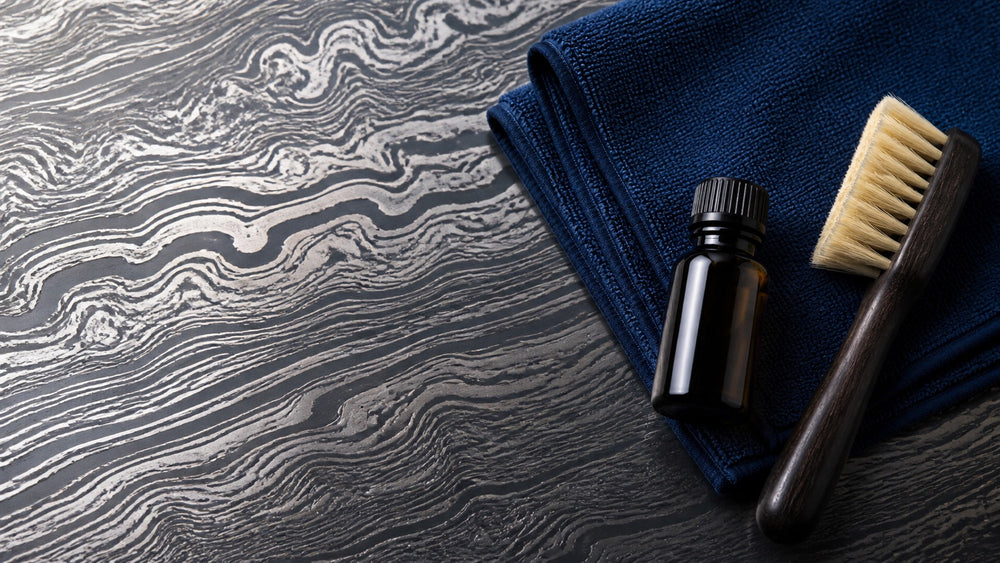Damascus-patterned steel with a microfiber cloth, oil bottle, and cleaning brush