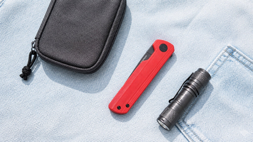 Closed red HOPIAN Clave knife with a compact pouch and flashlight on denim