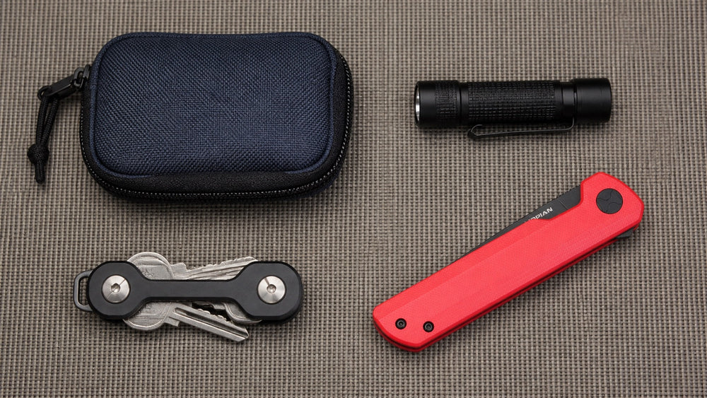 Closed red HOPIAN Clave knife with a pouch, key organizer, and flashlight