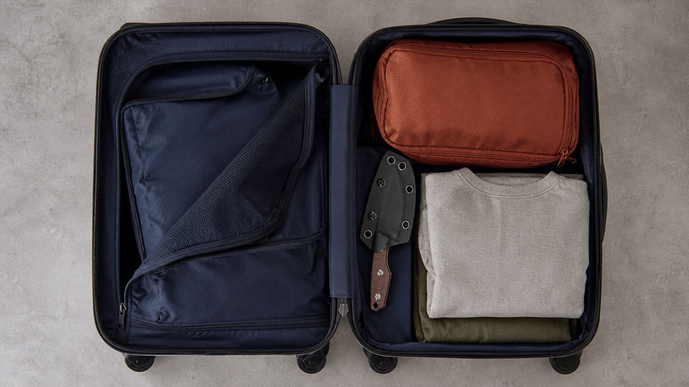 Sheathed brown HOPIAN Morrow knife secured inside an organized checked suitcase