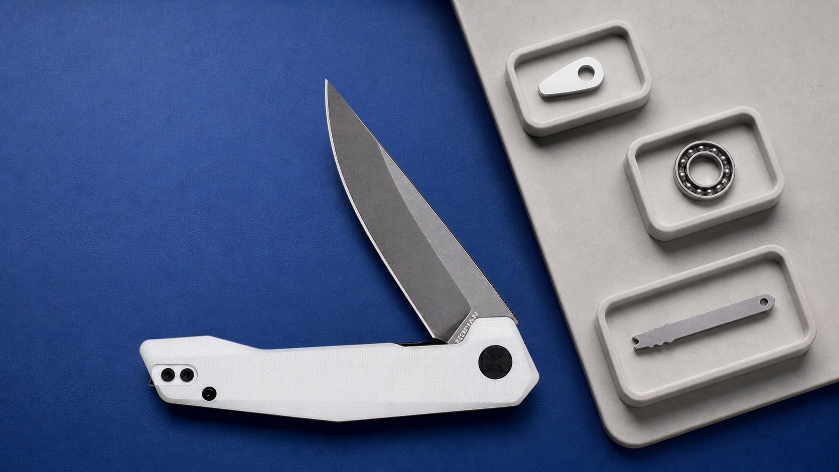 White HOPIAN VEX folding knife beside separate opener mechanism and lock samples