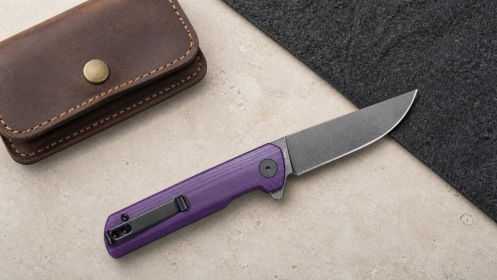 Open purple HOPIAN Clave knife beside a complete riveted leather pouch