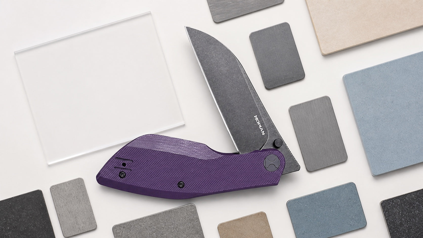 Purple HOPIAN Periodic folding knife on an overhead steel comparison table