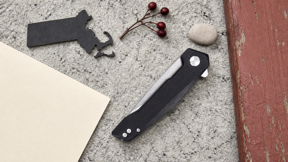 Closed black HOPIAN Vex knife in a neutral Massachusetts legal research scene