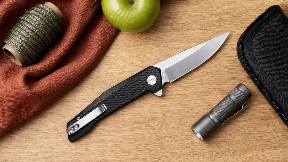 Open black HOPIAN Vex knife with cord, an apple, a pouch, and flashlight
