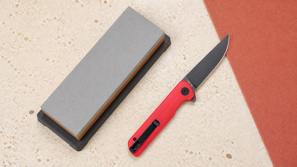 Open red HOPIAN Clave knife beside a complete bench sharpening stone